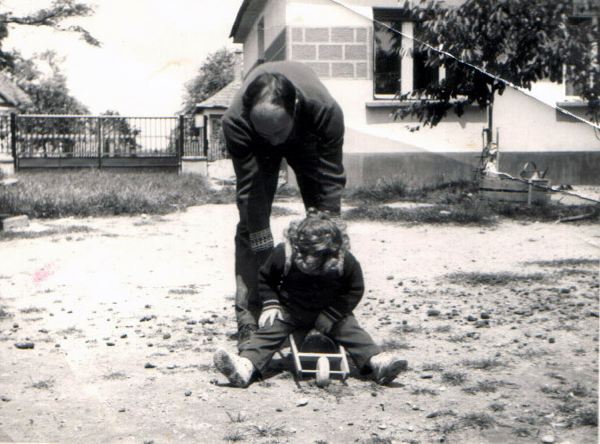 1980.  MÉ 2 előtt udvaron apuval talicskában ülős